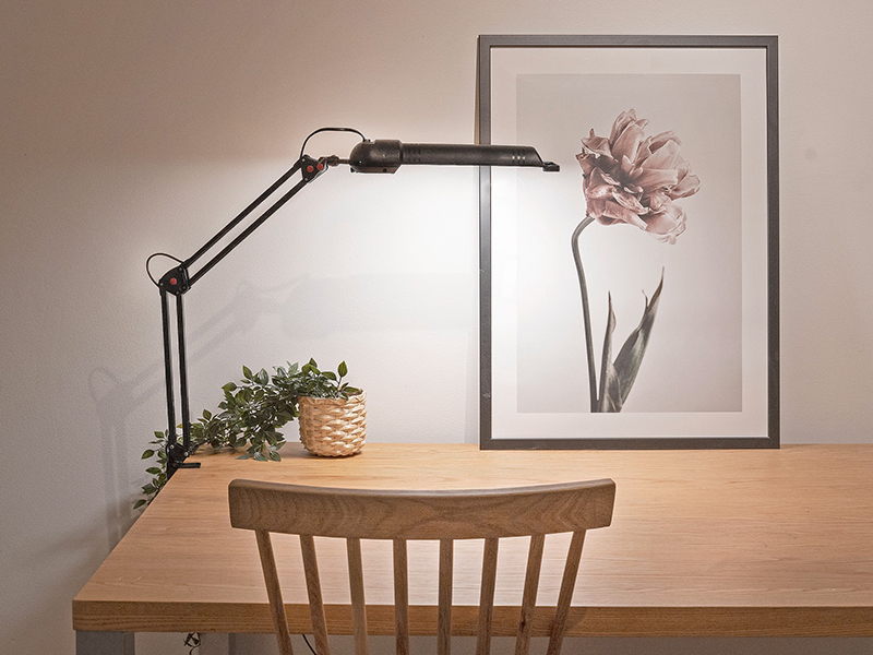 Black LED desk lamp attached to a wooden desk