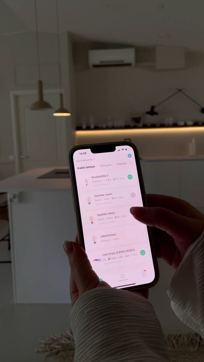 Keittiön saarekkeen yllä kaksi riippuvalaisinta, joista toisen valoa säädetään parhaillaan Airam SmartHome -sovelluksella. Taustalla hylly, jonka alle on kiinnitetty Airam SmartHome -lednauha. Molempiin valonlähteisiin säädettty pehmeä tunnelmavalo.